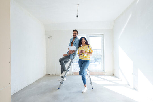 Happy couple with blueprint at new home