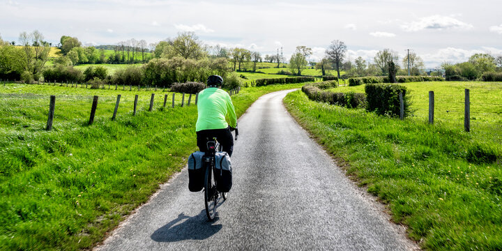 Senior man cycling on road near field on sunny day