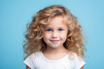 Close-up portrait of a cute little girl with blond curly hair on a blue background