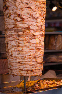 Close-up of grilled meat on a vertical grill is used in traditional street food doner kebab or shawarma. Vertical photo