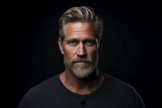 Portrait of a handsome mature man with a beard on a dark background.