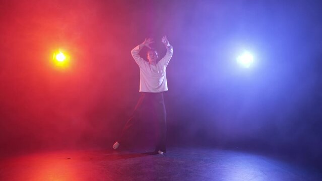 Young woman performing dance in studio. Expression girl dancing elegant contemporary performance in studio in multi-colored red blue spotlights. Motion dance, female professional dancer concept.