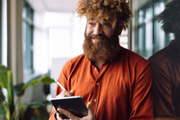 Smiling businessman holding tablet PC with digitized pen in office