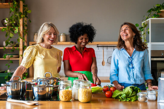 Happy women preparing food together in kitchen at home
