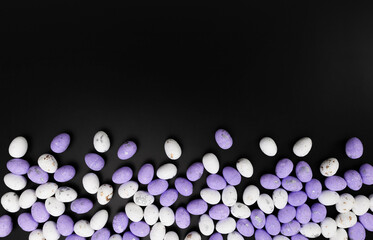 Top view of purple and white easter eggs on black background. Creative easter composition, spring, copy space, flat lay.