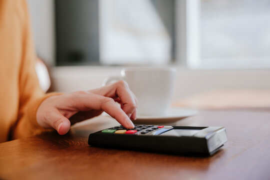 Hand of woman entering pin on credit card reader