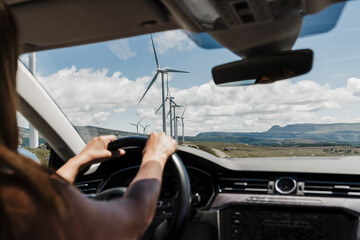 Spain, Madrid,Hands of woman driving past wind farm