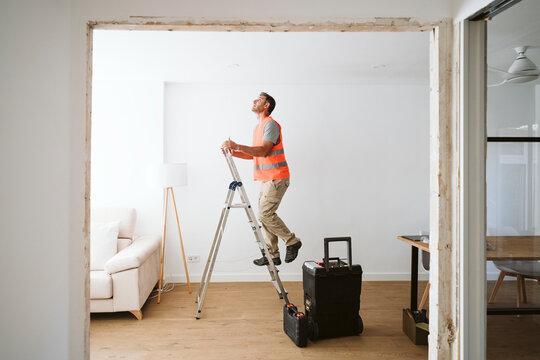Technician climbing on ladder in house under renovation