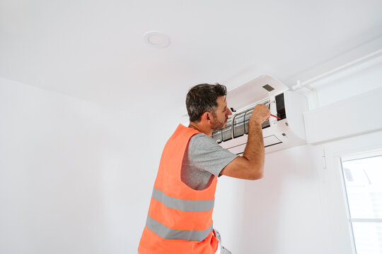 Electrician repairing air conditioner at home