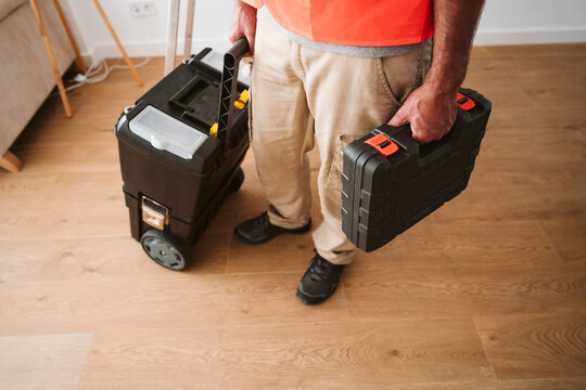 Repairman standing with tool boxes at house under renovation