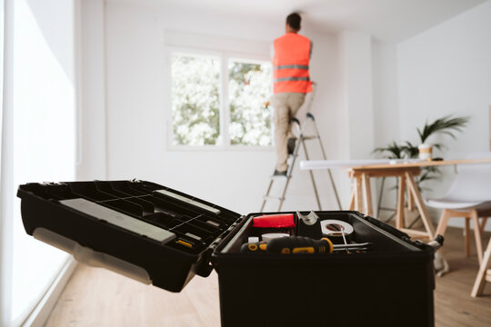 Open toolbox with repairman working in background at home