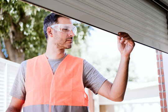 Repairman examining shutter at house under renovation