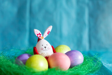 Colorful Easter eggs, green nest and bunny rabbit