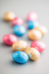 Easter chocolate eggs wrapped in aluminium foil on gray background.