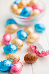 Easter chocolate eggs wrapped in aluminium foil on white table.