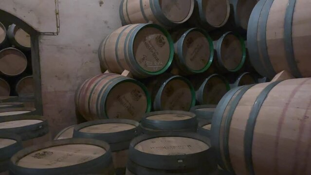 Aged wine barrels stacked in dim cellar. Vintage oak in winery storage