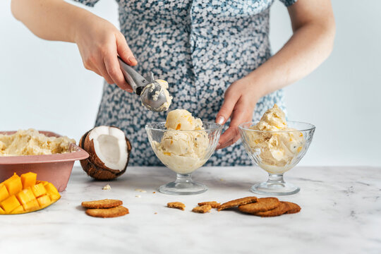 Mature woman scooping fruit ice cream in bowl on table