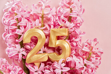 Number 25 twenty five golden celebration birthday candle on Pink flowers Background. 25 years birthday. concept of celebrating birthday, anniversary, important date, holiday hyacinth bouquet.