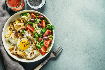 Healthy breakfast bowl with salad and fried eggs with mushrooms on table, top view with copy space