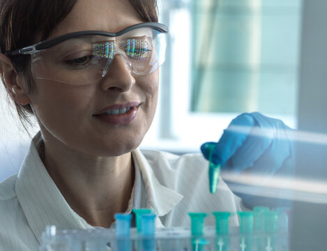 Smiling scientist placing DNA sample in eppendorf tube at laboratory