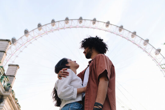 Young couple standing in front of Ferris wheel in London city - Powered by Adobe