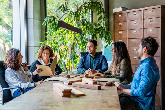 Creative professionals having discussion over wooden samples on desk in office