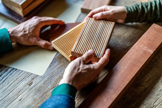 Hands of colleagues holding wooden sample in office