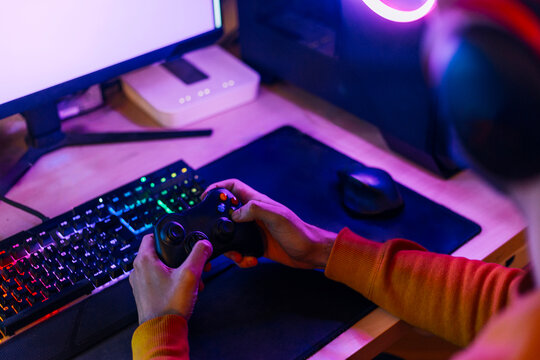 Gamer playing video games on computer at home