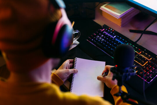 Influencer writing on note pad near keyboard at desk