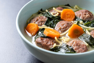Italian Wedding Soup with meatballs and spinach on black background. Close up
