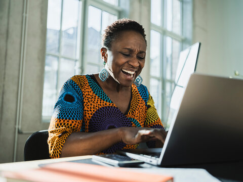 Screaming businesswoman using laptop at desk in office