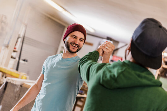 Happy craftsmen giving high-five at workshop - Powered by Adobe