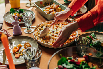 Hands of woman cutting savory pie on dining table at Easter dinner