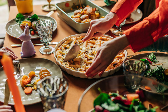 Hands of woman cutting savory pie on dining table at Easter dinner