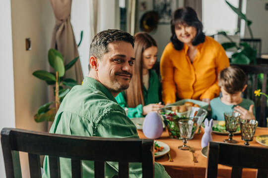 Smiling man looking over shoulder at Easter dinner with family