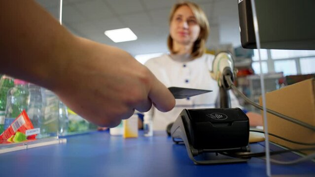Enlarged image of the terminal to which the card is presented for payment. A pharmacy worker in a uniform is very friendly. High quality 4k footage