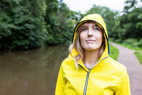 Smiling woman wearing yellow raincoat in forest