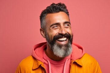 Portrait of happy bearded man laughing and looking at camera. Isolated on pink background