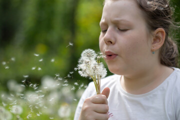 Summer joy - lovely girl blowing dandelion