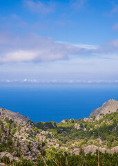Fototapeta na wymiar Amazing landscapes of Mallorca. The mountains are covered with greenery, the sea is blue and transparent. Sunny day, clouds over a rocky ridge. Mallorca, Spain, Balearic Islands