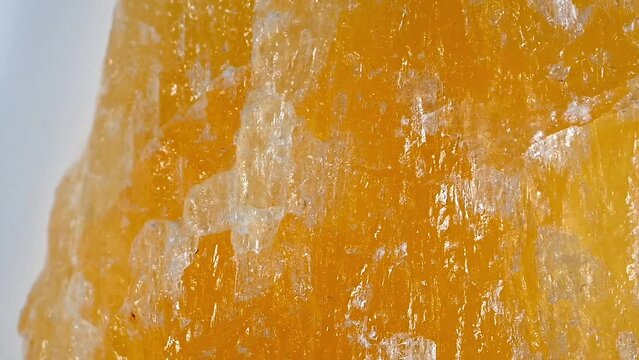 Yellow Calcite crystal sample rotating slowly against a white background	