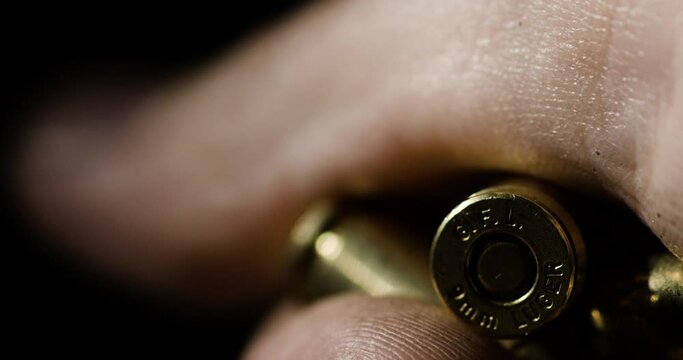 Macro detail closeup of  9&times;19mm Parabellum bullet held inside hand, rack focus