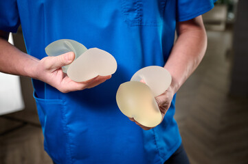 Close-up of female plastic surgeon demonstrates breast implants to a patient for her new breast....
