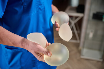 Close-up of female plastic surgeon demonstrates breast implants to a patient for her new breast....