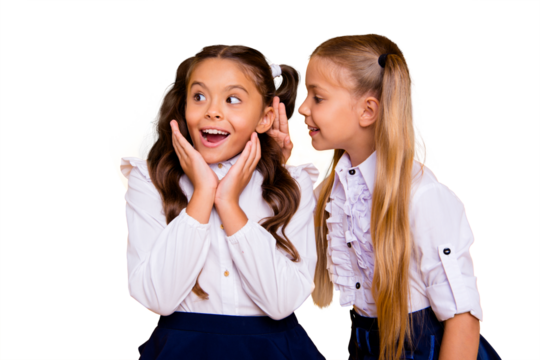 Close up portrait of small blonde girl isolated on vivid yellow background bent to tell the interesting news or secret of brunette friend with wow face