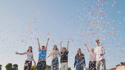 Friends toss colorful paper confetti from their hands.