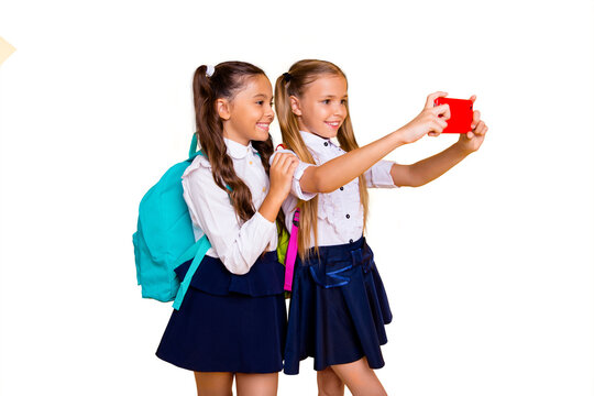 Profile side view photo of two charming, gorgeous, adorable, good-looking small girls make selfie on smartphone camera isolated on shine yellow background