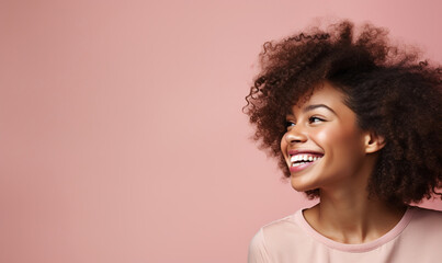 Obraz na płótnie Canvas Young black woman smiling with curly hair and a light-colored top, in front of pink background with copyspace