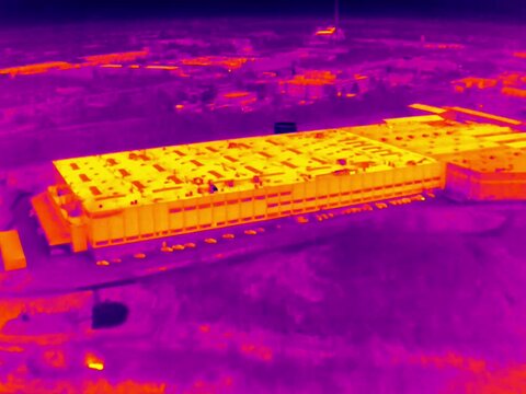 Aerial infrared thermal view of industrial zone with factories and warehouses, in purple and yellow hues
