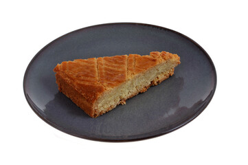 Portion triangulaire de gâteau traditionnel breton dans une assiette en gros plan sur fond blanc.